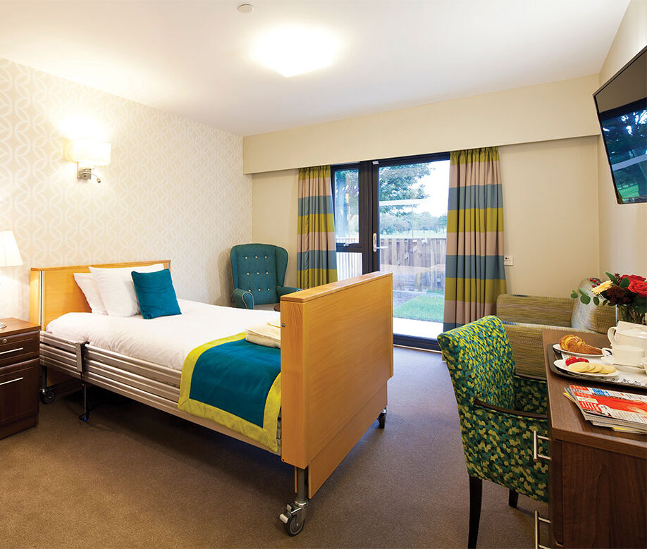 bedroom in a care home with teal bedsheets and curtains