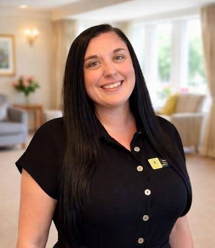 deputy manager smiling in a care home lounge in black shirt with dark hair