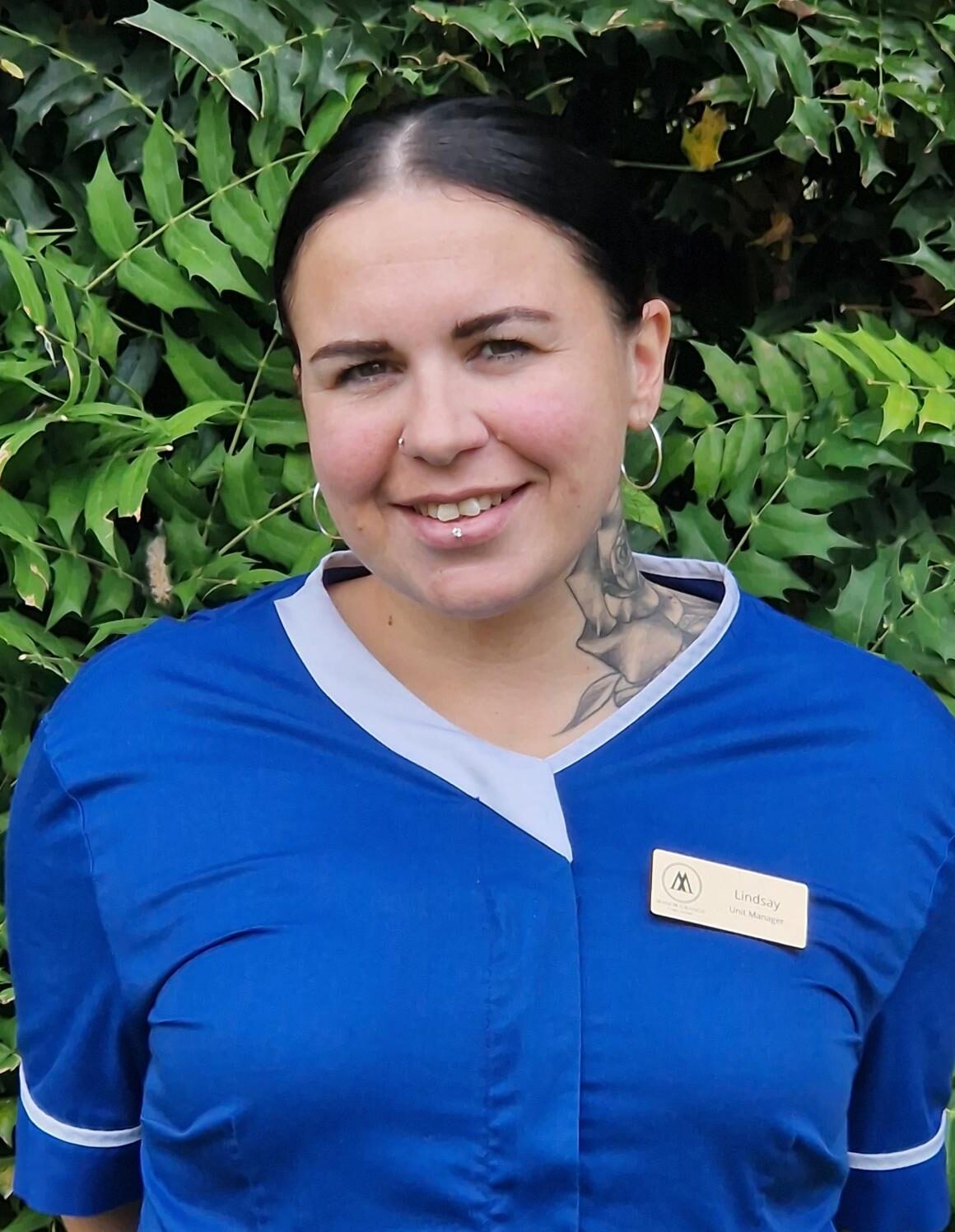 woman in dark blue nurse uniform smiling outdoors
