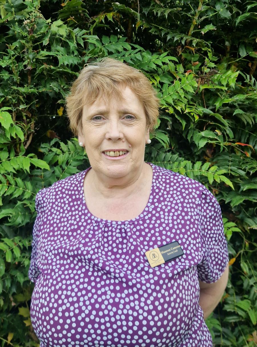 woman with short hair smiling in a green garden
