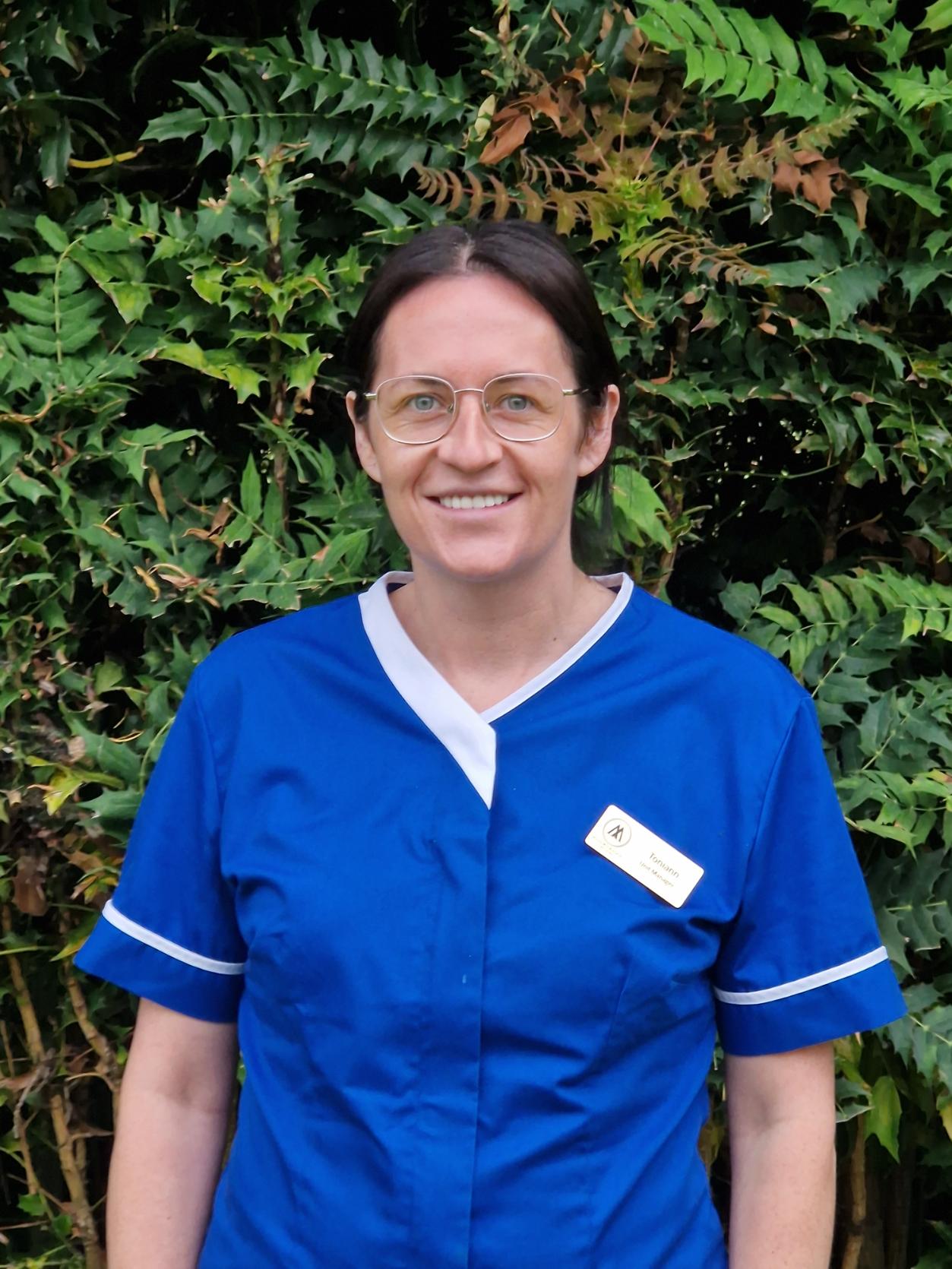 woman in dark blue nurses uniform smiling outdoors