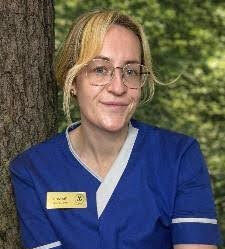 nurse smiling with blonde hair in blue uniform