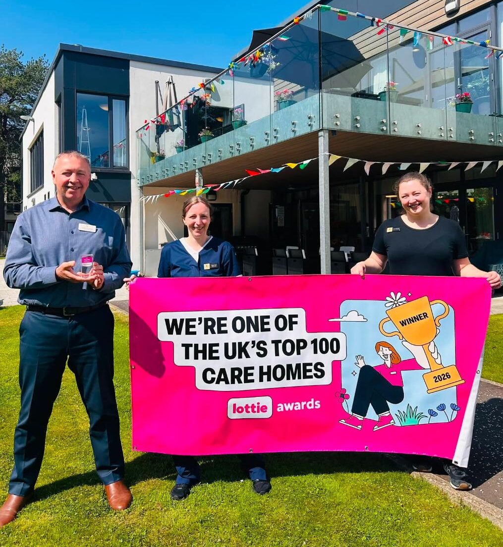 staff from manor grange care home smiling and holding Lottie Awards banner