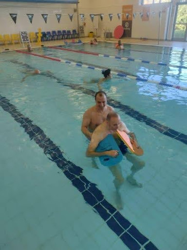care home resident swimming with a carer in a pool