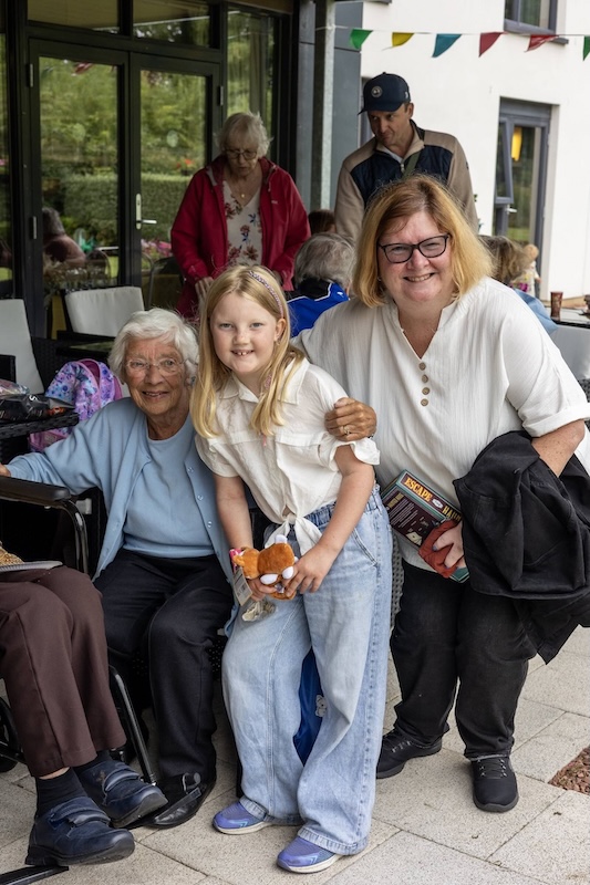 Woman, young girl, and elderly woman smile outside
