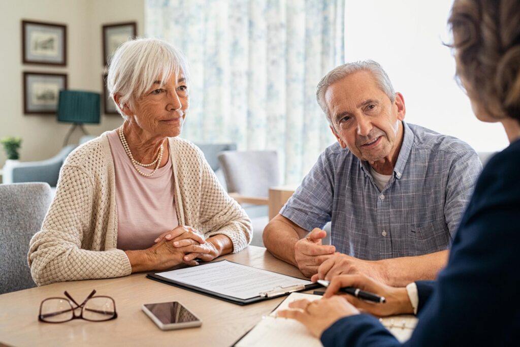 an elderly couple at a table talking to a care home staff member